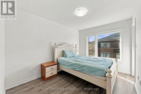 A bedroom with a bed, nightstand, and window.