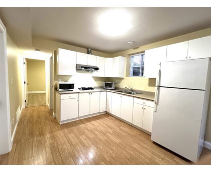 A kitchen with white cabinets and wooden floors.