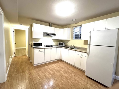 A kitchen with white cabinets and wooden floors.