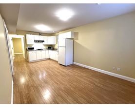 A kitchen area with wooden flooring and white appliances.