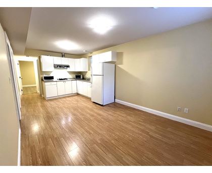 A kitchen area with wooden flooring and white appliances.
