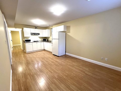 A kitchen area with wooden flooring and white appliances.