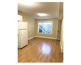 A white refrigerator in a room with wooden floors and a window.