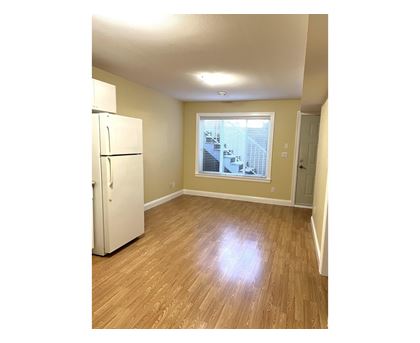 A white refrigerator in a room with wooden floors and a window.
