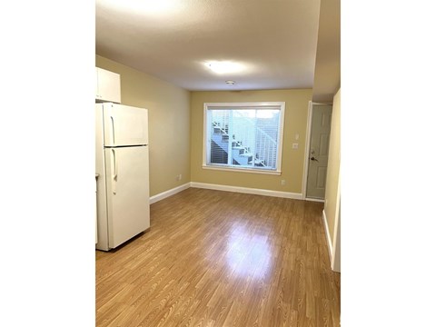 A white refrigerator in a room with wooden floors and a window.
