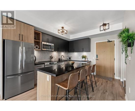 A modern kitchen with a black countertop and stainless steel appliances.