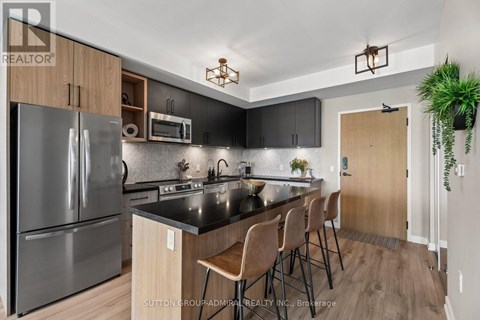 A modern kitchen with a black countertop and stainless steel appliances.