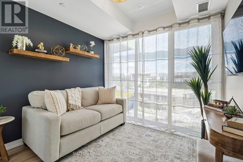 A living room with a grey couch and a large window.