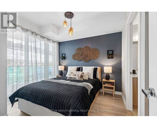 A bedroom with a large bed and a window with curtains.