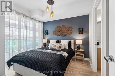 A bedroom with a large bed and a window with curtains.