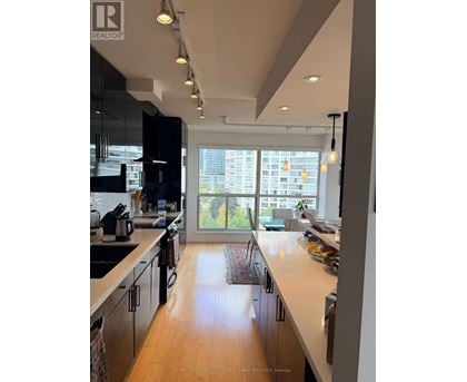 A modern kitchen with wooden floors and a large window.
