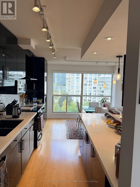 A modern kitchen with wooden floors and a large window.