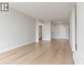A spacious room with wooden flooring and white walls.
