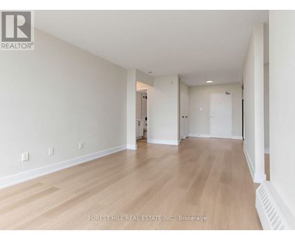 A spacious room with wooden flooring and white walls.