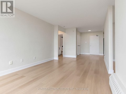 A spacious room with wooden flooring and white walls.