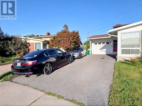 A black car is parked in front of a house with a garage.