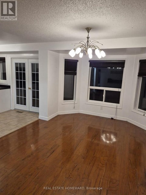 A room with wood flooring and a chandelier.