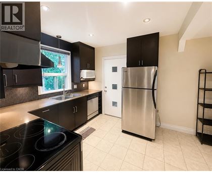 A modern kitchen with a stainless steel refrigerator and black cabinets.