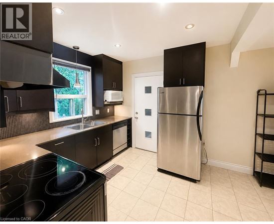A modern kitchen with a stainless steel refrigerator and black cabinets.