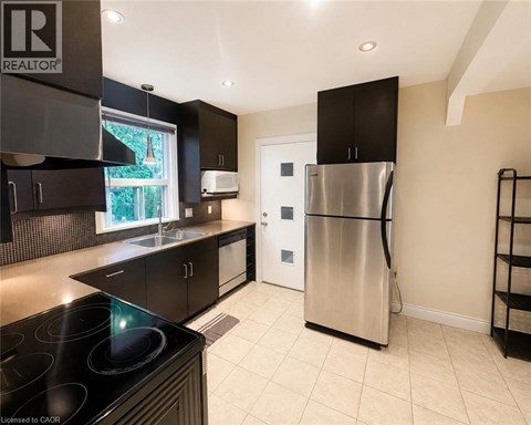 A modern kitchen with a stainless steel refrigerator and black cabinets.