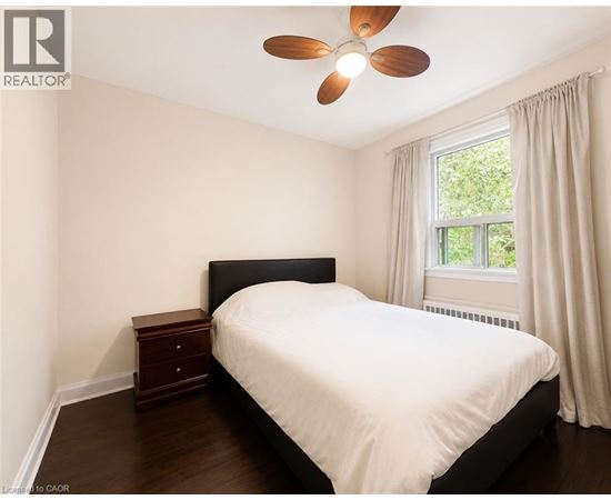 A bedroom with a bed, nightstand, and window.