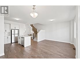 A spacious, empty room with wooden floors and white walls.