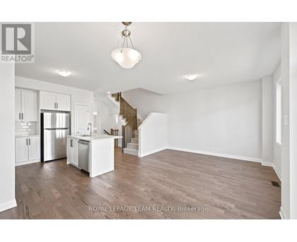 A spacious, empty room with wooden floors and white walls.