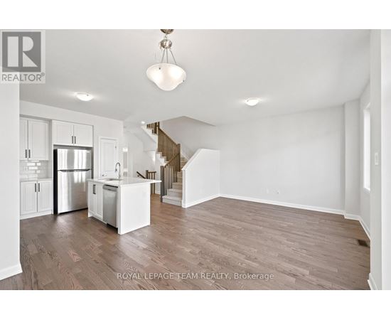 A spacious, empty room with wooden floors and white walls.