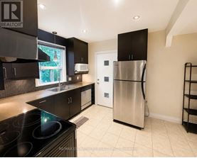 A modern kitchen with a stainless steel refrigerator and black cabinets.