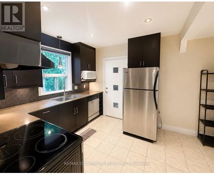 A modern kitchen with a stainless steel refrigerator and black cabinets.