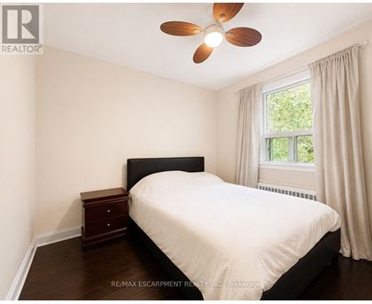 A bedroom with a bed, nightstand, and window.