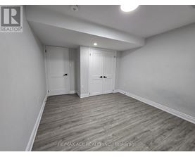 A room with wooden flooring and white walls, with two doors and a ceiling light.