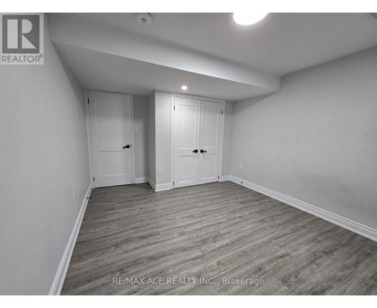 A room with wooden flooring and white walls, with two doors and a ceiling light.