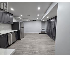 A spacious kitchen with stainless steel appliances and wooden flooring.