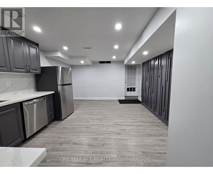 A spacious kitchen with stainless steel appliances and wooden flooring.