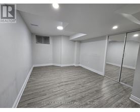 A spacious room with wooden flooring and white walls.