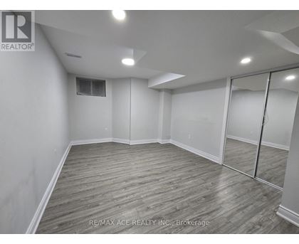 A spacious room with wooden flooring and white walls.