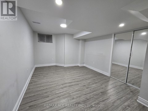 A spacious room with wooden flooring and white walls.