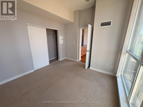 A room with a carpeted floor and a window on the right side.