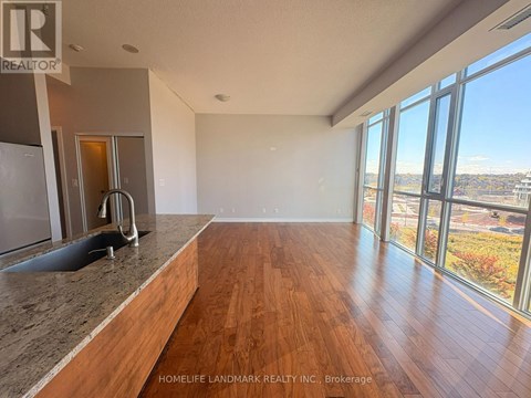 A spacious room with wooden floors and large windows overlooking a cityscape.