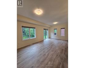 A spacious room with wooden flooring and windows.