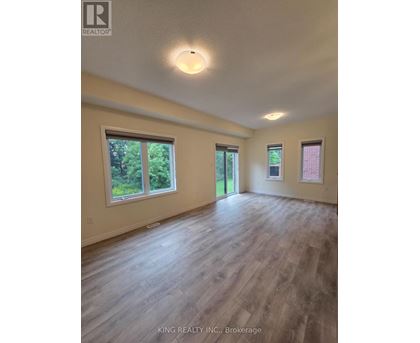 A spacious room with wooden flooring and windows.