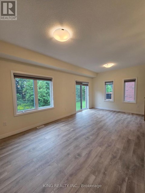 A spacious room with wooden flooring and windows.