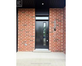 A black door with a glass window is set in a brick wall.