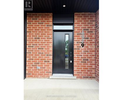 A black door with a glass window is set in a brick wall.