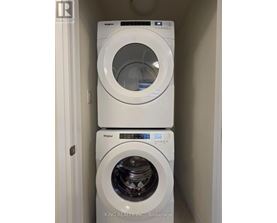 Two white Whirlpool washing machines stacked on top of each other.