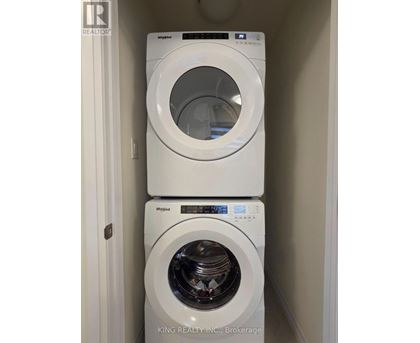 Two white Whirlpool washing machines stacked on top of each other.