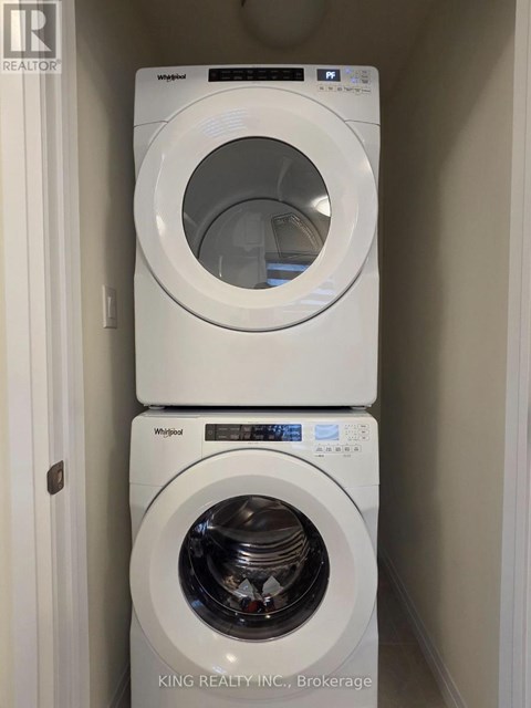 Two white Whirlpool washing machines stacked on top of each other.
