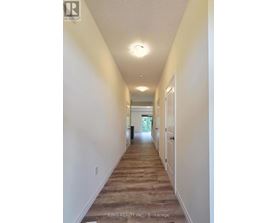 A long hallway with white walls and wood flooring.