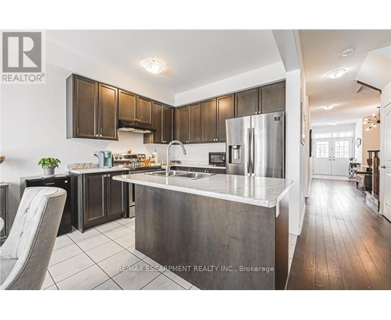 A modern kitchen with dark wood cabinets and stainless steel appliances.